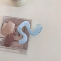 Detail of a translucent light blue S-shaped wave hair claw clip on a CD cover background - Blue