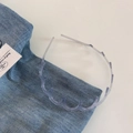 Close-up of transparent wavy plastic headband with teeth on blue denim fabric background - Transparent Gray