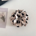 Detail of cream fabric scrunchie with large black polka dots on textured background - Off-white