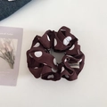 Detail showing dark brown polka dot scrunchie with happiness fabric tag and soft texture - Coffee/Brown