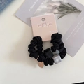 Close-up of black scrunchie with acrylic squares and golden logo charm on display card - Two-Piece Set / Black Series
