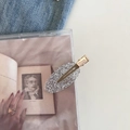 Dettaglio di fermaglio per capelli dorato con superficie ovale glitterata su sfondo artistico - Argento