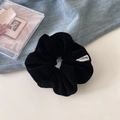 Detail of premium black velvet scrunchie featuring a white woven label and soft texture - Black