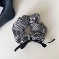 Detail of checkered houndstooth scrunchie with a black bow and pearl pendant charm - Black and White Grid Bow Scrunchie