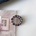 Detailaufnahme des rot-schwarz karierten Strick-Haargummis auf minimalistischem Hintergrund - Schwarz