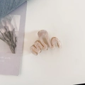Primer plano de pinza de pelo ondulada en S con textura de mármol rosa y muelle dorado - Beige
