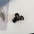 Detalle de la pinza para el pelo ondulada en negro y oro sobre un fondo estético - Negro