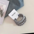 Detailopname van twee donkergrijze satijnen haarelastiekjes op een merkverpakking - Geplooide Scrunchie / Grijsblauw