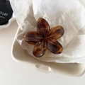 Detailed close-up of a vintage amber floral hair claw clip on a ceramic display tray - Dark Tortoiseshell