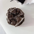 Grand chouchou à carreaux marron avec liseré blanc sur un présentoir minimaliste - Café