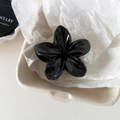 Detalle de una pinza para el cabello de flor negra brillante en una bandeja de joyas minimalista - Negro