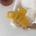 Macro shot of a glossy ginger yellow resin hair claw clip on soft white textured paper - 7# Ginger