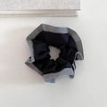Detail view of a black satin scrunchie with houndstooth plaid pattern edges and texture - Black