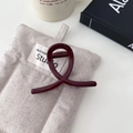Dettaglio di una pinza per capelli in resina bordeaux con design incrociato su sfondo - Stile a Y Medio