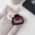 Dettaglio di un fermaglio per capelli geometrico rosso scuro su borsa in lino grigio - Stile Quadrato Piccolo