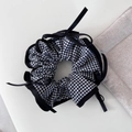 Dettaglio scrunchie a quadretti vichy con piccoli fiocchi su sfondo di tessuto bianco - Quadri Neri Con Fiocco in Nastro Nero
