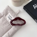 Dettaglio del fermaglio per capelli ondulato rosso scuro su una borsa in lino grigio - Stile Irregolare Piccolo