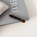 Vue macro d'une barrette baguette en acétate avec motif écaille de tortue et logo doré - Café Bleu (10#)