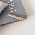 Détail de la barrette baguette en acétate marbré avec feuilles d'or sur un livre - Café Beige (8#)