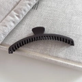 Detalle de pinza para el pelo negra mate con dientes largos sobre un libro blanco - 1# Café Gris Oscuro