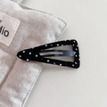 Detailed view of black polka dot fabric covered cloud hair clip on a linen bag - Triangle Style