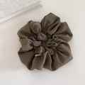 Macro detail of brown oversized scrunchie with a gold metal handmade tag and soft fabric folds - Green