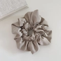 Detail of greige satin scrunchie featuring a premium rectangular silver metal tag - Beige Apricot