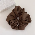 Detailed macro view of the premium brown satin scrunchie with a golden logo tag - Brown