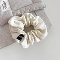 Detalle de un coletero de tela crema con textura de lino y etiqueta tejida negra chic - Beige