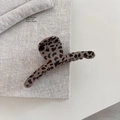 Detailweergave van een bruine haarklem met luipaardprint op een minimalistische tafel - Bar Stijl