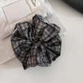 Macro-detail van de retro grijze geruite scrunchie met zachte stoftextuur en vintage ontwerp - Grijs-zwart geruit