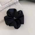 Close-up of a black oversized puffy scrunchie on a gray book with textured fabric - 4# Black