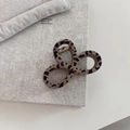 Detailed view of leopard print hair claw clip with golden metal spring on book - Figure 8 Knot Style