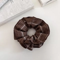 Dettaglio di un elastico per capelli retrò marrone scuro con righe e motivi geometrici - Caffè