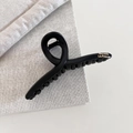Detail shot of a matte black hair claw with gold Barrette La France text on fabric - Black Crossed Style