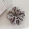 Detail eines grauen Strick-Scrunchies mit weicher Rippstruktur und Markenetikett-Webung - Haferflockengrau