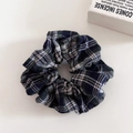 Gros plan d'un chouchou à carreaux bleu marine et vert avec texture en tissu rétro - Chouchou Carreaux Noir Vert