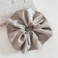 Détail d'un chouchou en cuir gris clair avec motif matelassé et coutures de précision - Beige