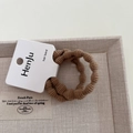 Détail macro d'élastiques à cheveux marrons avec design tissé texturé et étiquette papier - Kaki