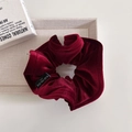 Macro detail of wine red velvet scrunchie with Blind For Love label on display tray - Red