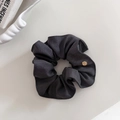 Detail eines dunkelgrauen Haargummis aus Streifenstoff mit goldenem Metallanhänger - Dunkelgrauer Scrunchie Stil