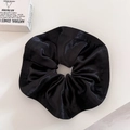 Macro shot of oversized black satin scrunchie showing glossy texture and elegant folds - Black