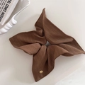Détail d'un chouchou en tissu rayé marron avec un petit médaillon doré de marque - Style Foulard Café