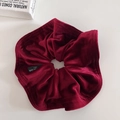 Detailed close-up of premium red velvet hair scrunchie with fine stitching and label - Burgundy