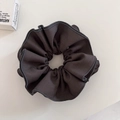 Detail shot of the pleated texture and hemmed edge on a dark grey fabric scrunchie - Gray