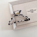 Close-up of zebra pattern fabric wrapped metal hair claw clip on beige display tray - White Zebra Pattern Fan Style