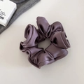 Détail du chouchou élégant en satin violet poudré avec un fini brillant et des plis soyeux - Violet Grisâtre