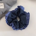 Detalle de coletero de tela escocesa azul y denim con textura plisada en mesa blanca - Coletero de Mezclilla