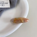 Detailopname van een amberkleurige marmeren acetaat haarklem met gouden gravering - Irillerend Oranje (3#)