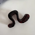 Détail macro d'une pince à cheveux ondulée motif écaille avec finition polie et dents - Café Foncé